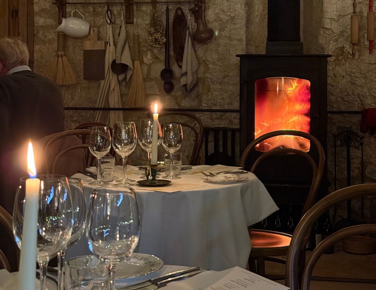 Small dinner tables are set up with glasses and plates, with a burning candle on each table.