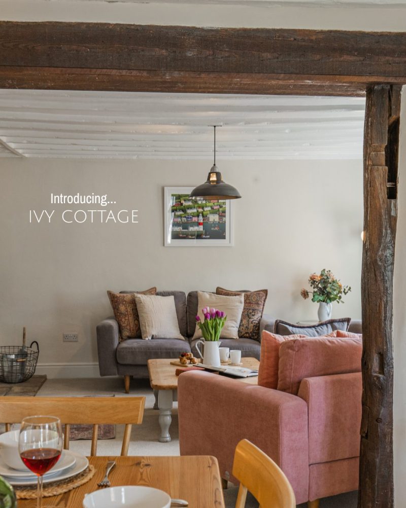 Brown and soft pink furnishings with a large wooden coffee table can be seen through an exposed beam archway.